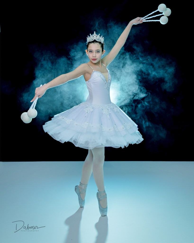 Ballet dancer in white on pointe with smoke behind her