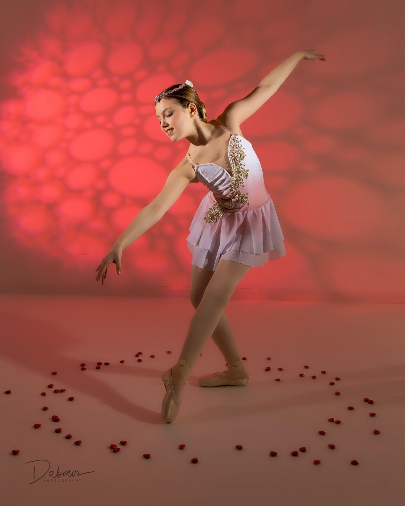 Ballet dancer striking a beautiful pose with rose petals on the floor