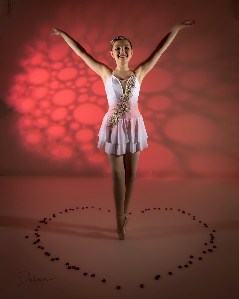 ballet dancer on point with her arms raised standing in the middle of a valentine