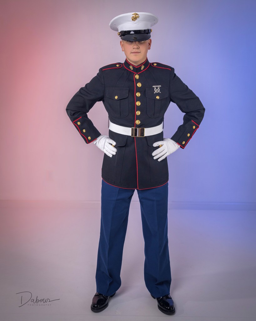 A side-by-side comparison of a U.S. Marine posing in two different uniforms: the Service Charlie tan shirt and blue trousers on the left, and the formal Dress Blue uniform with white cover on the right.