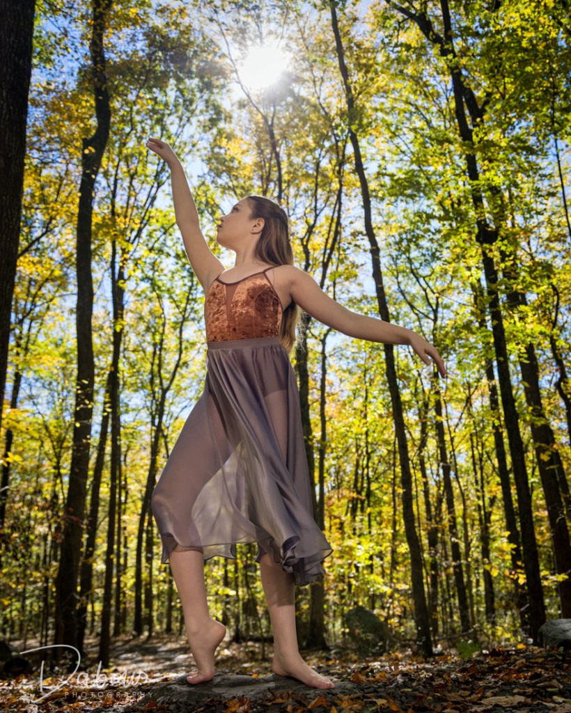 Vivi Taggart performing a graceful ballet pose among the ancient-style stone megaliths at Columcille Megalith Park.