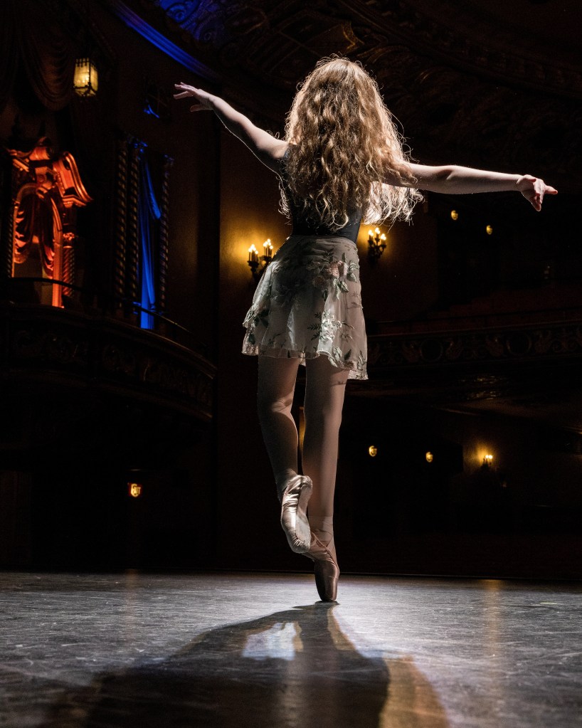 Dabour Photography dance ambassadors, including Lily, posing together in the ornate lobby of the State Theatre of the Arts. The dancers are in various ballet poses against the gold-leaf and velvet decor.