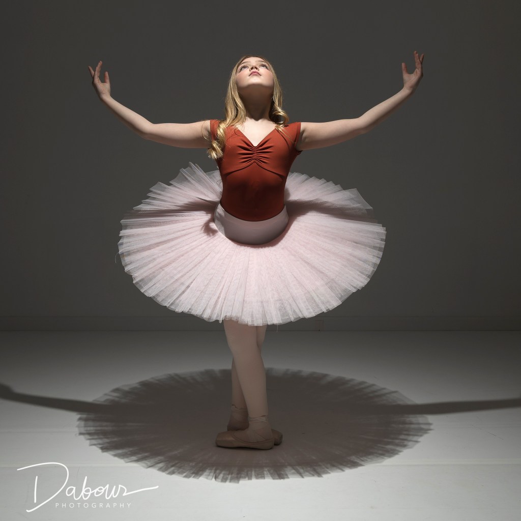 Fine art dance portrait of Vivi Taggart using dramatic low-key studio lighting to highlight her form and technique.
