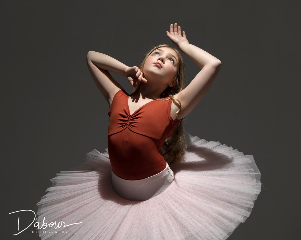 Fine art dance portrait of Vivi Taggart using dramatic low-key studio lighting to highlight her form and technique.