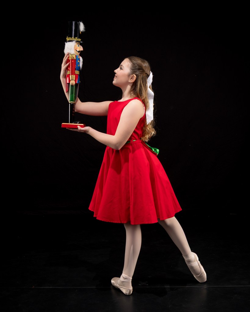 Vivi Taggart in a classical Nutcracker ballet costume and headpiece, posing for a holiday-themed studio portrait.