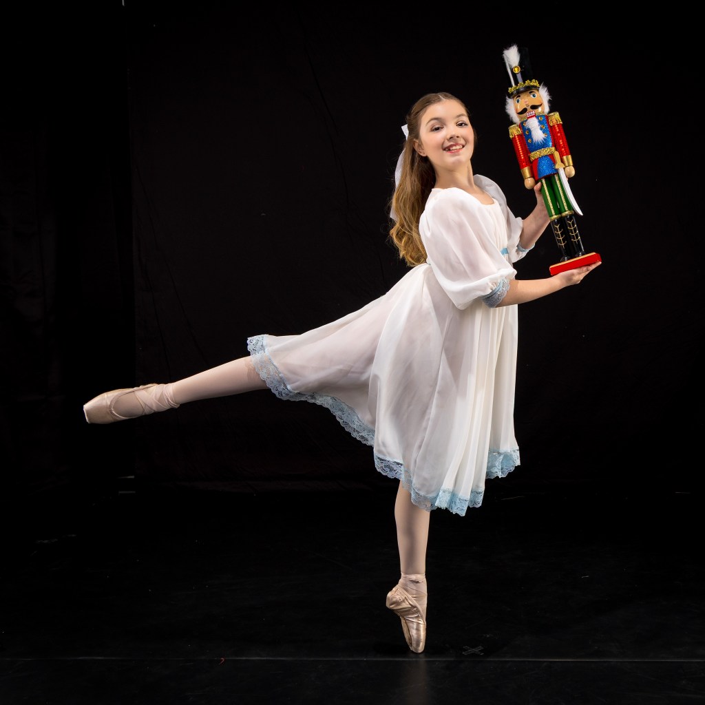 Vivi Taggart in a classical Nutcracker ballet costume and headpiece, posing for a holiday-themed studio portrait.